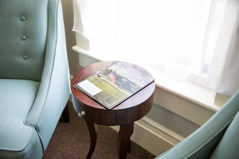 The image features a cozy living room setting with a green armchair, a coffee table, and a magazine on top of the table.